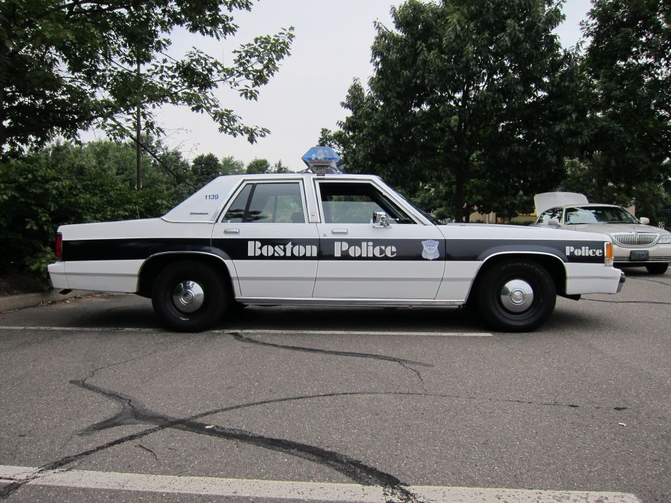 White 1991 Ford Crown Victoria LTD police car, side view, with black stripe and 'Boston Police' text