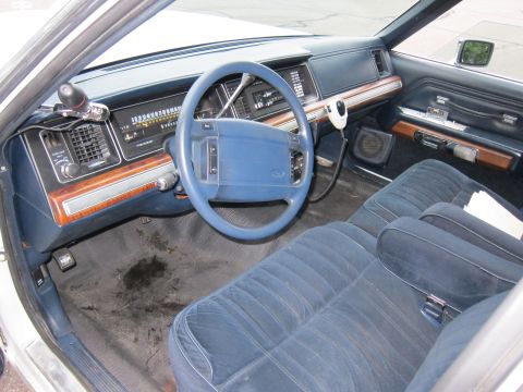 1991 Ford LTD Crown Victoria - The interior of the car features blue velour seats and a wood-grain dashboard with a CB radio.