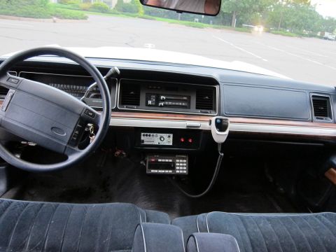 1991 Ford LTD Crown Victoria - The interior of a 1991 Ford Crown Victoria LTD police car is visible, equipped with a radio and microphone.