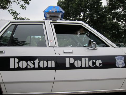 1991 Ford LTD Crown Victoria - A Boston Police car is shown from the side, the text 'Boston Police' and a police emblem on the door.