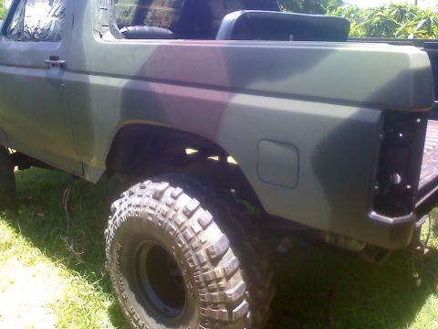 1990 Ford Bronco - This camouflaged SUV features large off-road tires and appears to be undergoing some form of modification or restoration.