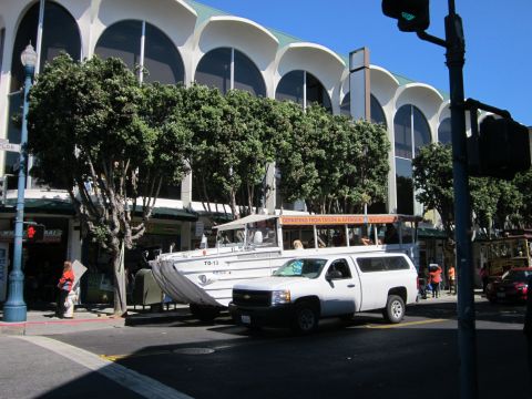 1991 Ford LTD Crown Victoria - A white pickup truck and an amphibious tour bus are seen on a city street with buildings in the background.