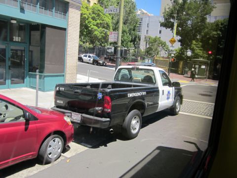 1991 Ford LTD Crown Victoria - Police pickup truck with "EMERGENCY 911" on the door is parked on a city street.