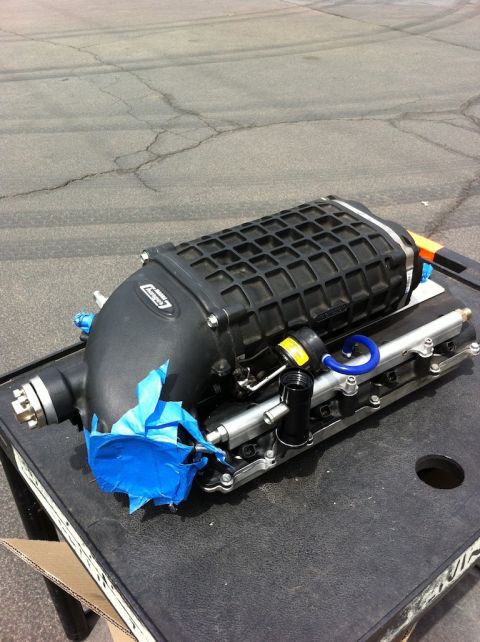 2010 Dodge Challenger - A supercharger assembly is shown resting on a table, with blue tape covering a portion of the intake manifold.