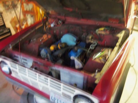 1968 Ford Bronco - The engine bay of a red 1968 Ford Bronco is visible with the hood up, revealing the engine and various components.