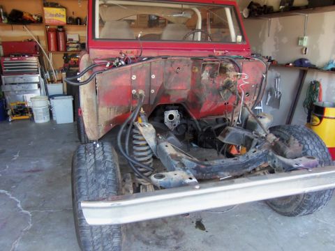 1968 Ford Bronco - This red SUV is partially disassembled in a garage, revealing its chassis and engine bay.