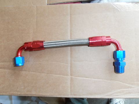 1990 Ford Bronco - A braided fuel line with red and blue fittings is laid out on a cardboard surface.