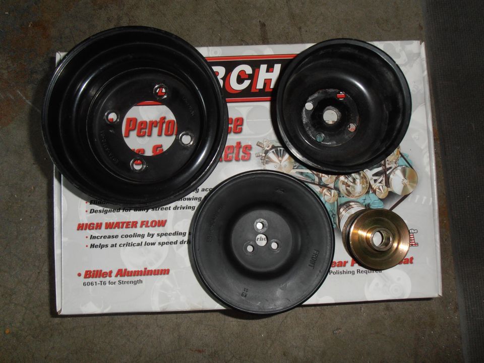 Three black water pump pulleys and a brass pulley on a box