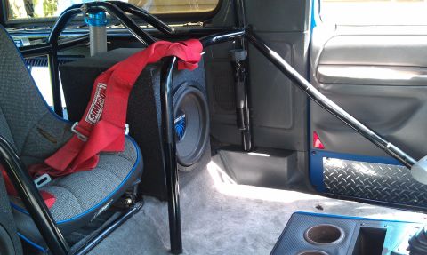 1984 Ford Bronco - This modified vehicle interior features a roll cage, racing seat, and a prominent subwoofer installation.