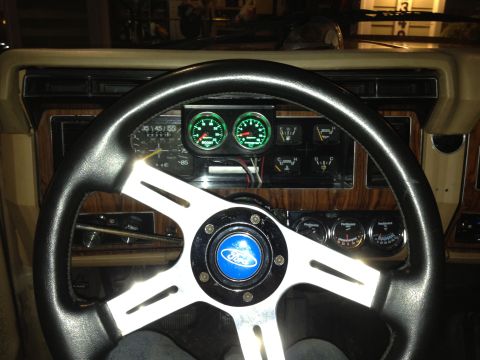 1984 Ford Bronco - The interior of a 1984 Ford Bronco features a Ford steering wheel and aftermarket gauges.