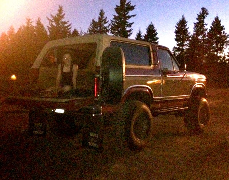 Maroon and tan Ford Bronco with lifted suspension and spare tire on the back