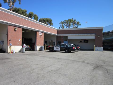 1991 Ford LTD Crown Victoria - Two police vehicles are parked in front of a commercial building on a sunny day.