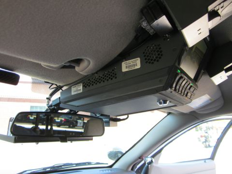 1991 Ford LTD Crown Victoria - Interior view of a police vehicle's overhead equipment console and a reflection of patrol cars in the rearview mirror.