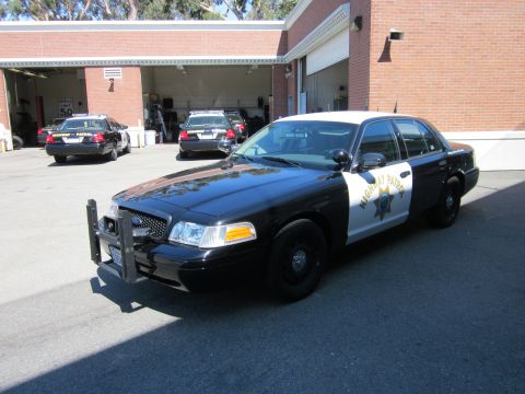 1991 Ford LTD Crown Victoria - A California Highway Patrol car is parked in front of a building, with other patrol cars visible in the background.