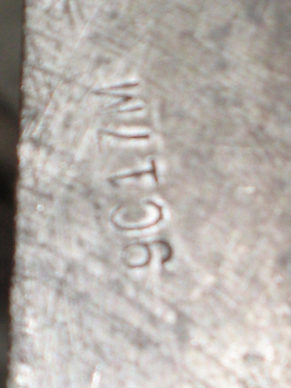 Close-up of a metal part with stamped numbers 'WJ T 96'