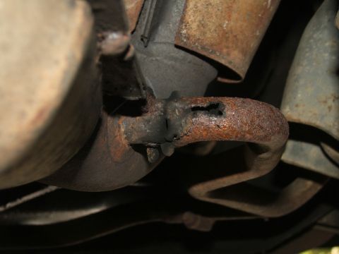 1988 Ford Crown Victoria LTD - A close-up view of a heavily rusted exhaust pipe showing significant damage and a hole.