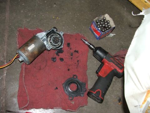 1988 Ford Crown Victoria LTD - Disassembled car window motor and associated parts laid out on a red shop towel next to a power tool.