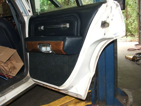 1988 Ford Crown Victoria LTD - Close-up of a car's interior door panel, wood trim and black upholstery.