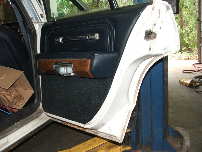 Interior door panel with wood trim and black upholstery