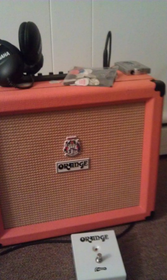Orange guitar amplifier with headphones and guitar picks on top