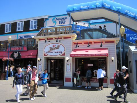 1991 Ford LTD Crown Victoria - People walk past shops and attractions on a pier, including the Aquarium of the Bay.