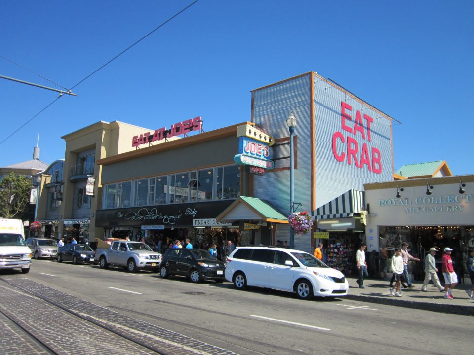 Street view with businesses like Joe's and Eat Crab, cars and a white minivan parked along the road