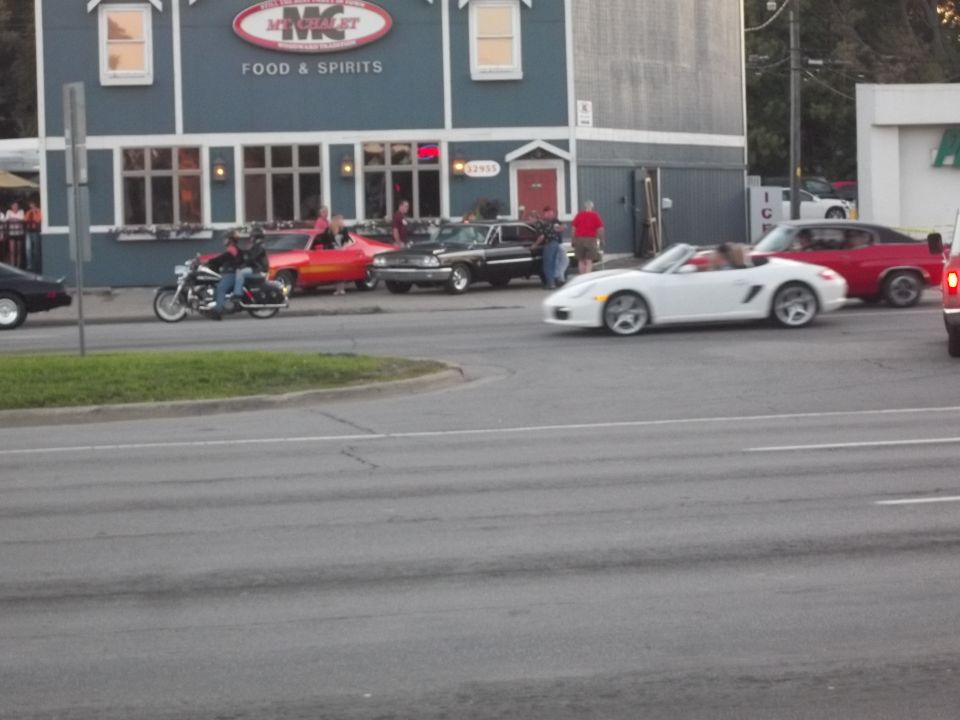 Several cars and a motorcycle parked in front of a building