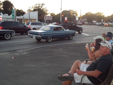 1970 Ford Ranchero - A blue 1964 Ford Falcon coupe is seen driving on a street with other vehicles and people nearby.
