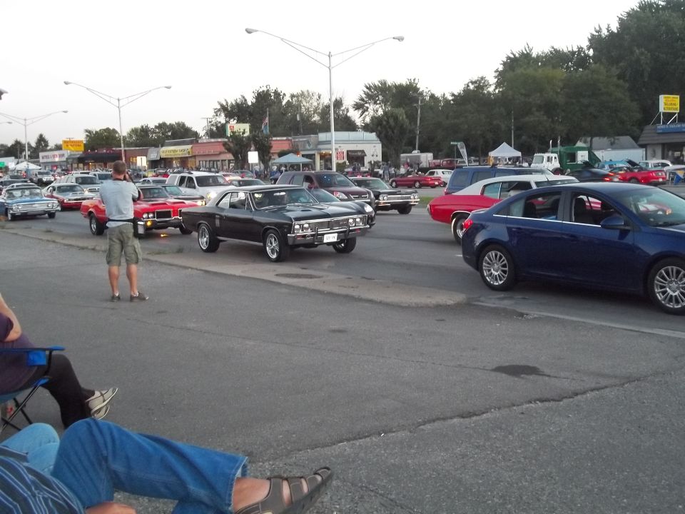 guy taking photo of black muscle car, other cars in lot
