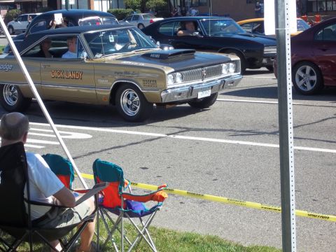 1970 Ford Ranchero - A gold 1967 Dodge Coronet with a black vinyl roof and hood scoop is seen from the front-three-quarter angle.
