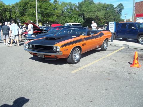 1970 Ford Ranchero - This orange and black convertible muscle car features bold racing stripes and a prominent hood scoop, suggesting a powerful performance mod…