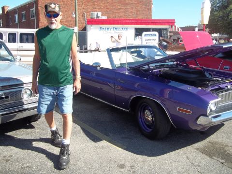 1970 Ford Ranchero - A man stands beside a purple 1970 Dodge Challenger convertible at an outdoor car show.