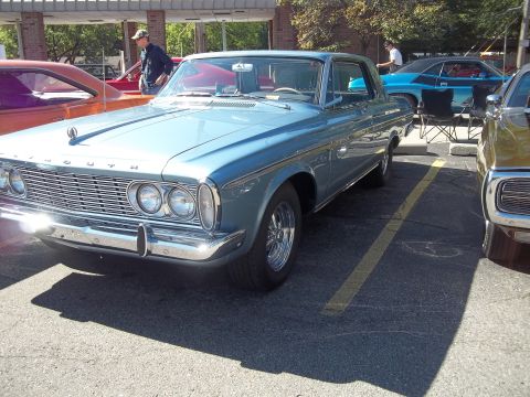 1970 Ford Ranchero - A light blue 1964 Plymouth Fury coupe is parked in a lot next to other vehicles.