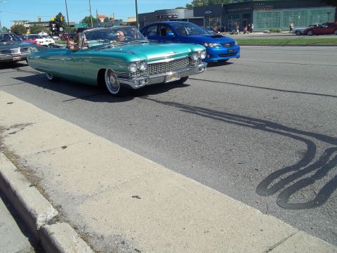 1970 Ford Ranchero - A teal 1960s Cadillac convertible cruises down the road with a blue Subaru following.