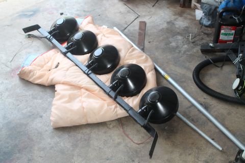 1990 Ford Bronco - A light bar with five black lights is shown resting on a blanket, with a vacuum hose and metal pole nearby.