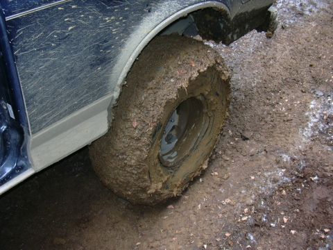 1991 Ford Bronco - Vehicle stuck in mud, showing a heavily mud-covered tire and fender.