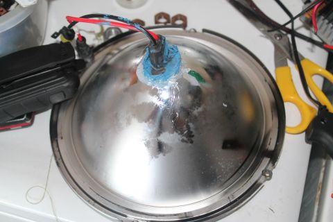 1990 Ford Bronco - This is a close-up of a chrome automotive headlight assembly with wires attached.