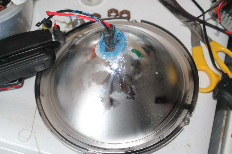 Close-up of a chrome automotive headlight assembly with wires attached