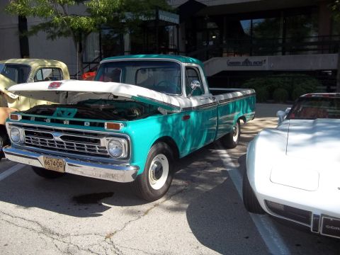 1970 Ford Ranchero - Turquoise and white pickup truck with hood open, showing its 1965 grille and parked next to a white sports car.