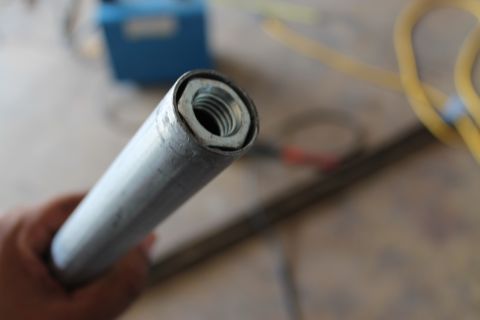 1990 Ford Bronco - A close-up shot shows a metal pipe with a nut secured inside its opening, with a hand holding the pipe.