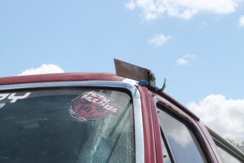 1990 Ford Bronco - A custom metal cleaver is attached to the roofline of a red vehicle.