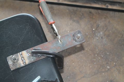 1990 Ford Bronco - A metal bracket is being welded while clamped to a black surface in a workshop.