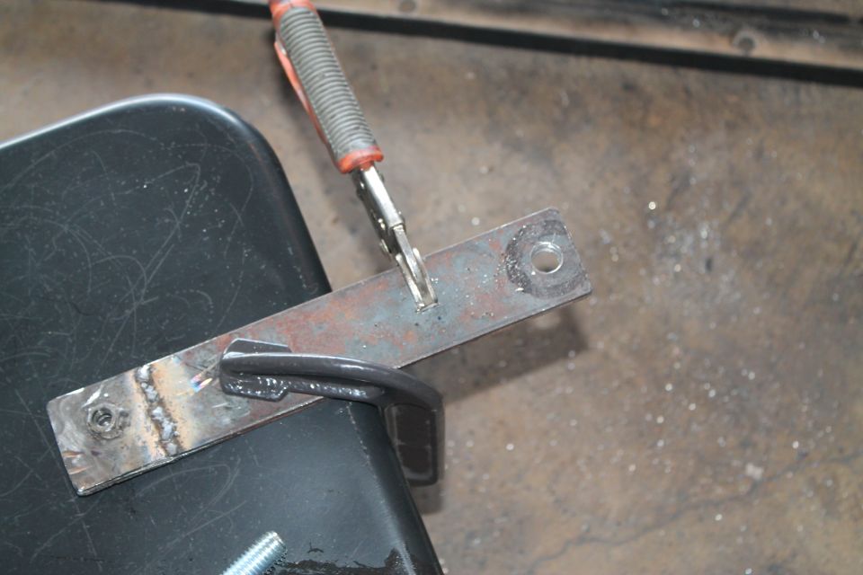metal bracket clamped to black surface, being welded