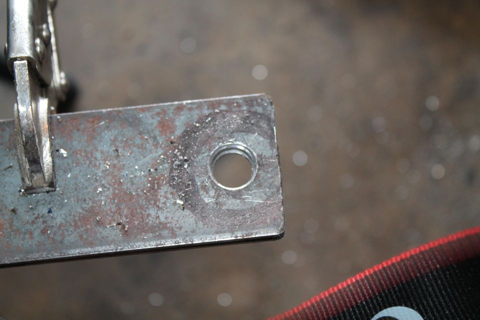 Metal bracket with a threaded hole, held by a clamp. Supermotors logo visible
