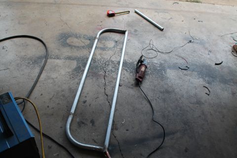 1990 Ford Bronco - Metal tubing and tools are laid out on a concrete floor, suggesting fabrication work.