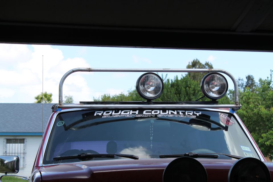 1990 Ford Bronco front view with roof-mounted light bar and two off-road lights. 'ROUGH COUNTRY' sticker visible on windshield