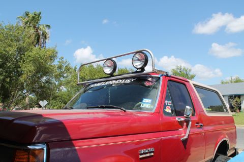 1990 Ford Bronco - 1990 Ford Bronco with a roof-mounted light bar and spotlights under a partly cloudy sky.