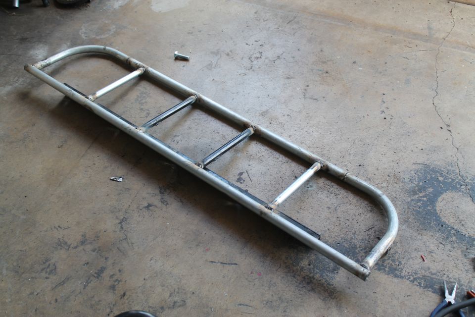 Custom metal light cage with multiple horizontal bars, lying on a concrete floor