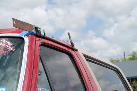 1990 Ford Bronco - A close-up view of a custom metal bracket mounted on the roof of a red vehicle.