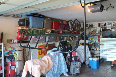 1990 Ford Bronco - A black metal light cage is suspended from the ceiling in a cluttered garage.